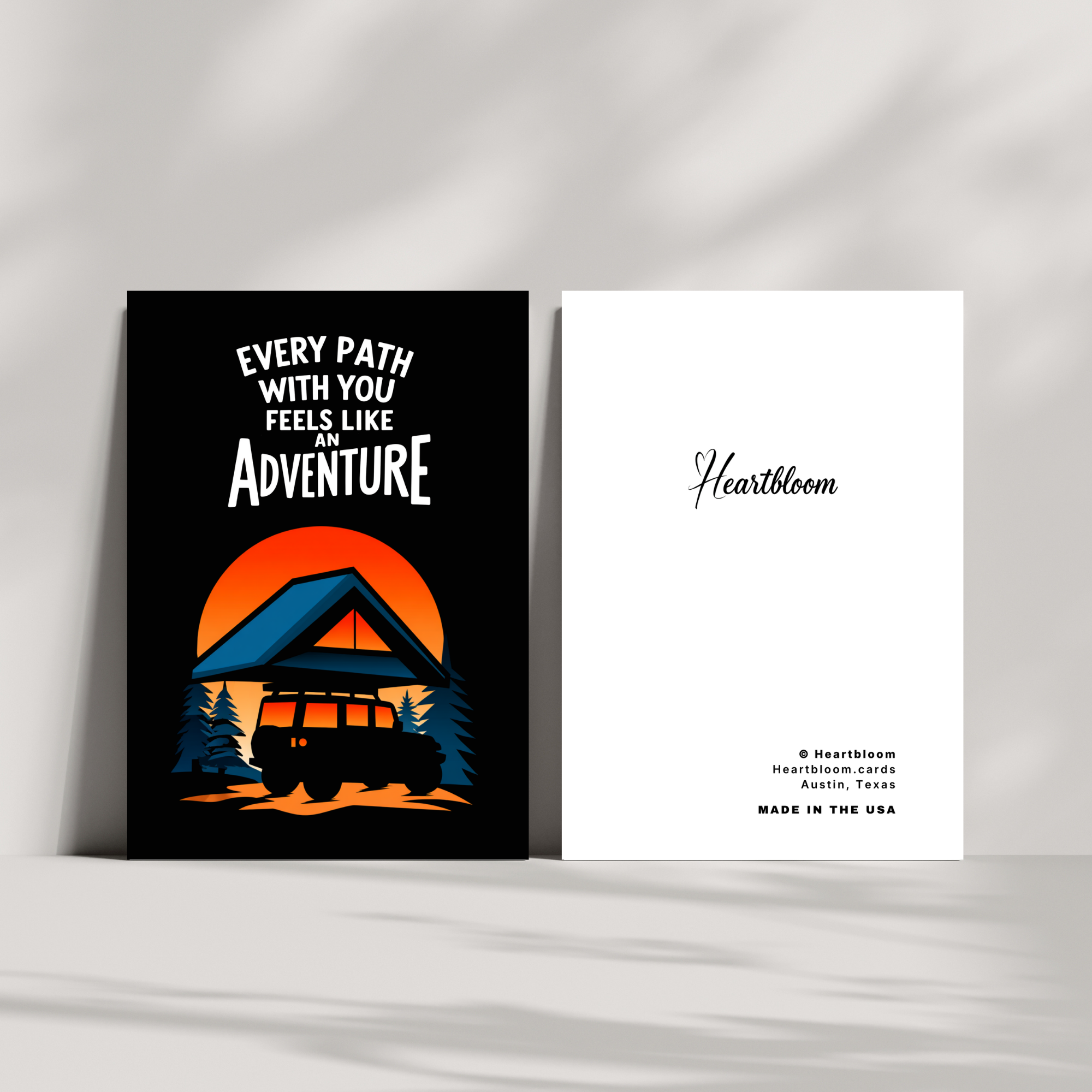 Card with 'Every path with you feels like an adventure' text and a silhouette of a car and sunset, with 'Heartbloom' branding on a white background.