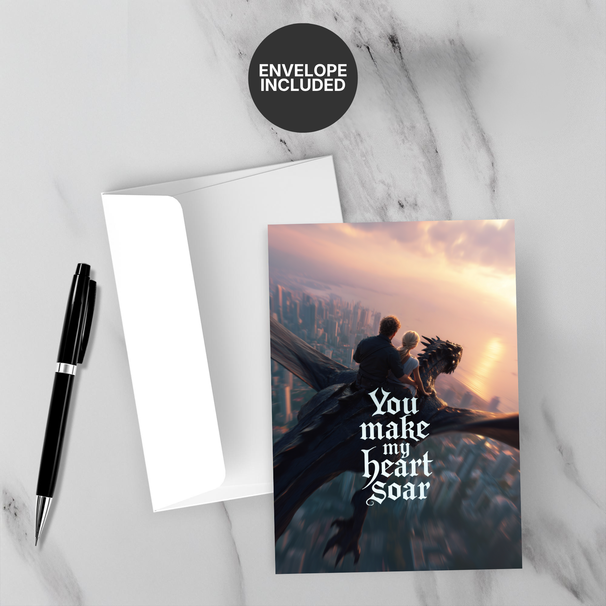 Greeting card with a couple on a dragon and 'You make my heart soar' text, accompanied by a pen and envelope on a marble surface.