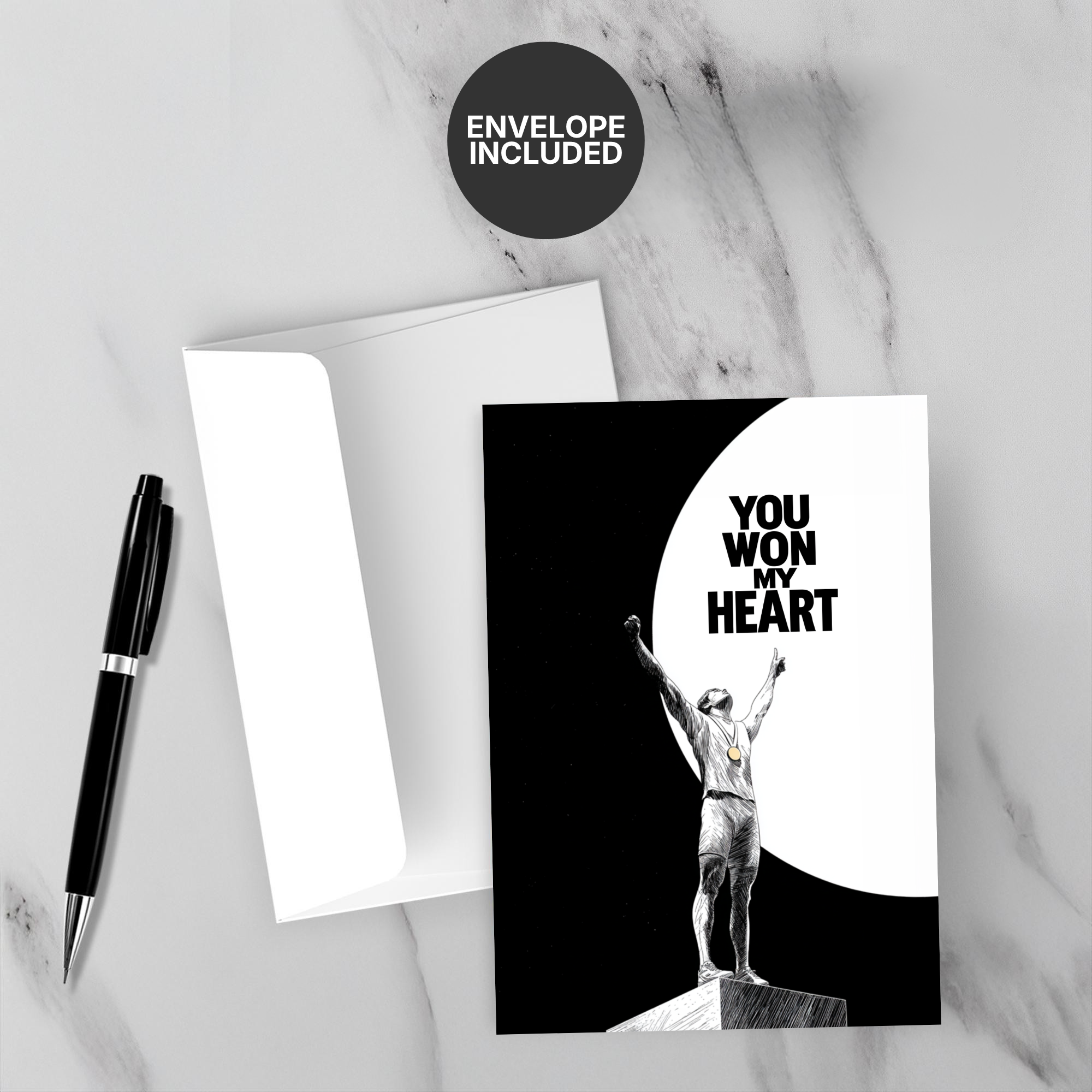 Greeting card with 'You Won My Heart' text and a statue silhouette, accompanied by a pen and envelope on a marble surface.