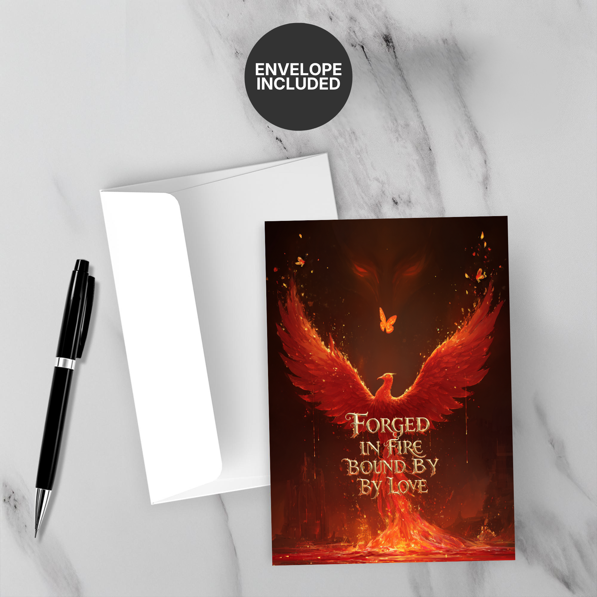 Greeting card with phoenix design and text 'Forged in Fire, Bound by Love' on a marble surface with a pen and envelope.