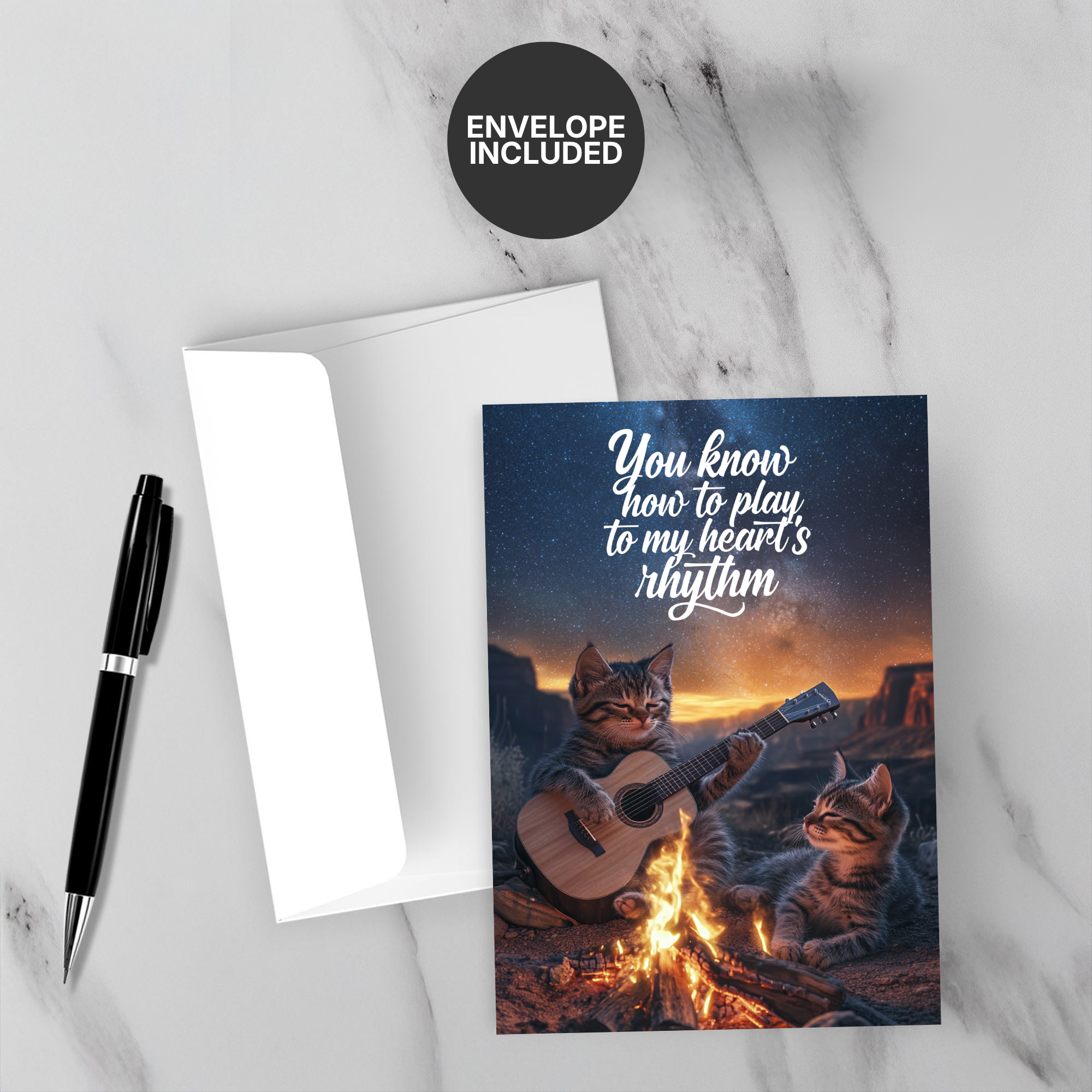 Greeting card with two cats playing guitar by a campfire, envelope included on marble surface