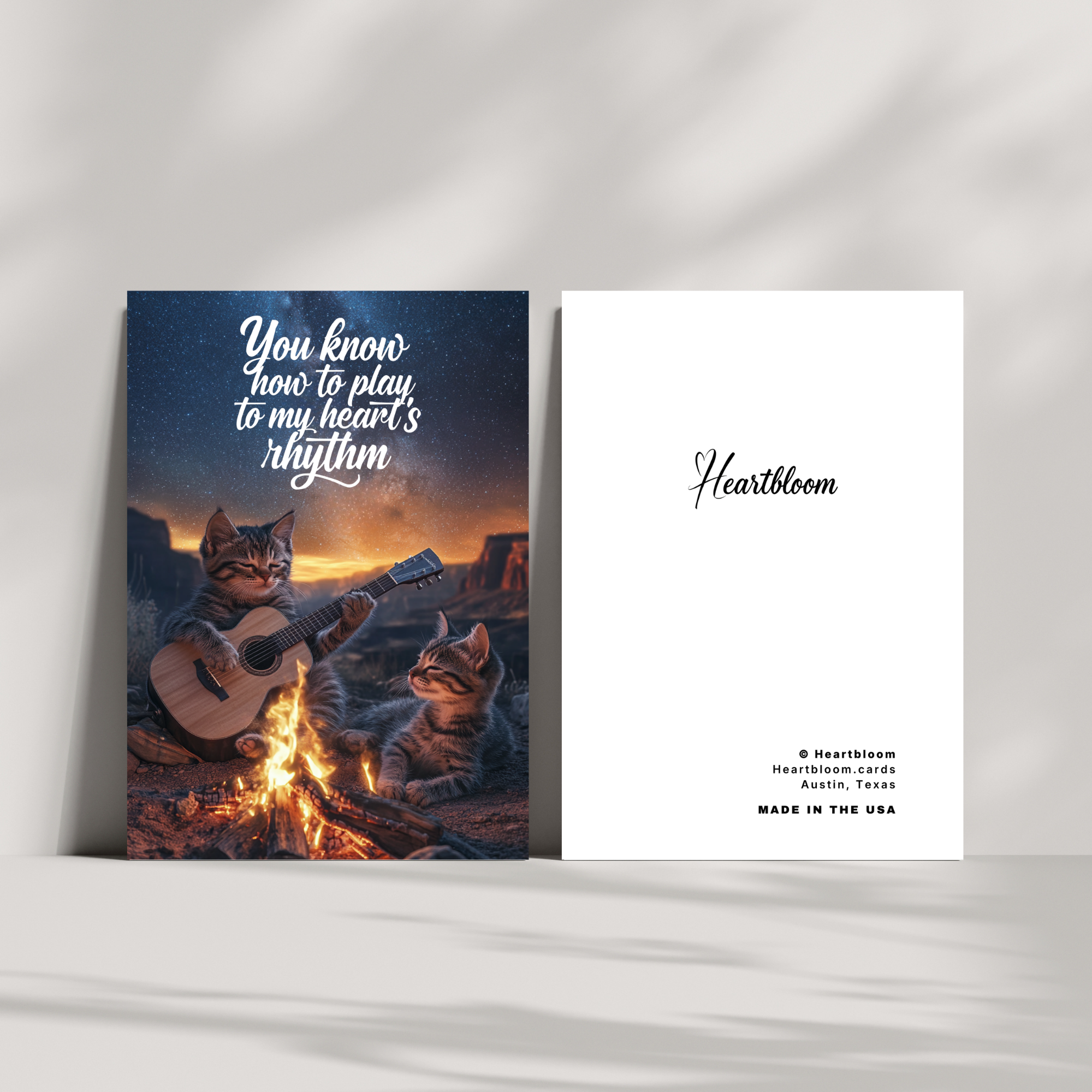 Two greeting cards with a cat playing guitar by a campfire and 'Heartbloom' branding.