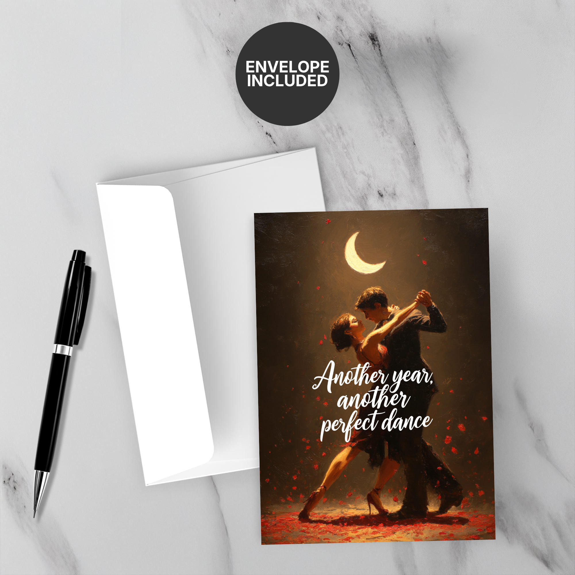 Greeting card with couple dancing under a moon, envelope, and pen on marble surface