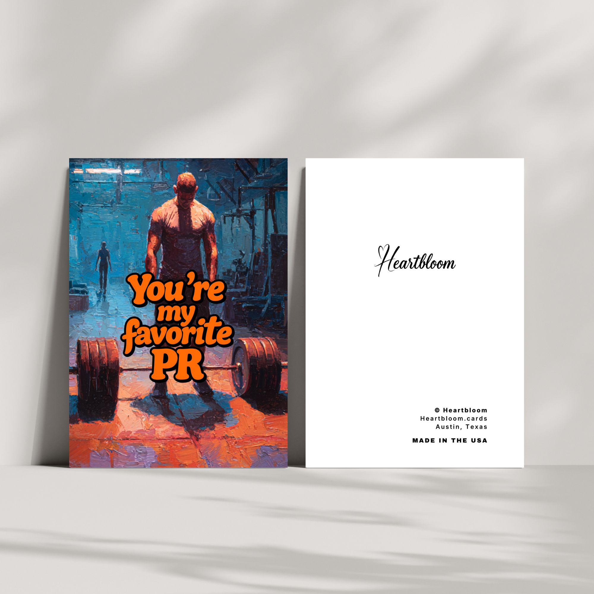 Two greeting cards on a white surface, one with a graphic design and text "You're My Favorite PR" gym theme, the other with branding.