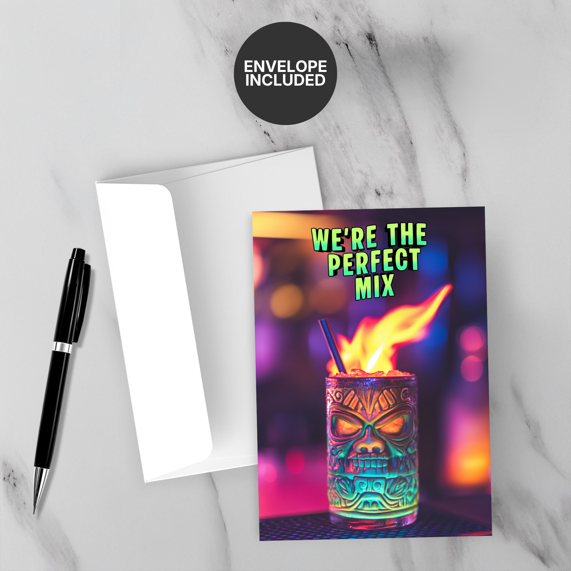 Greeting card with a colorful drink design and 'We're the Perfect Mix' text, accompanied by a pen and envelope on a marble surface.