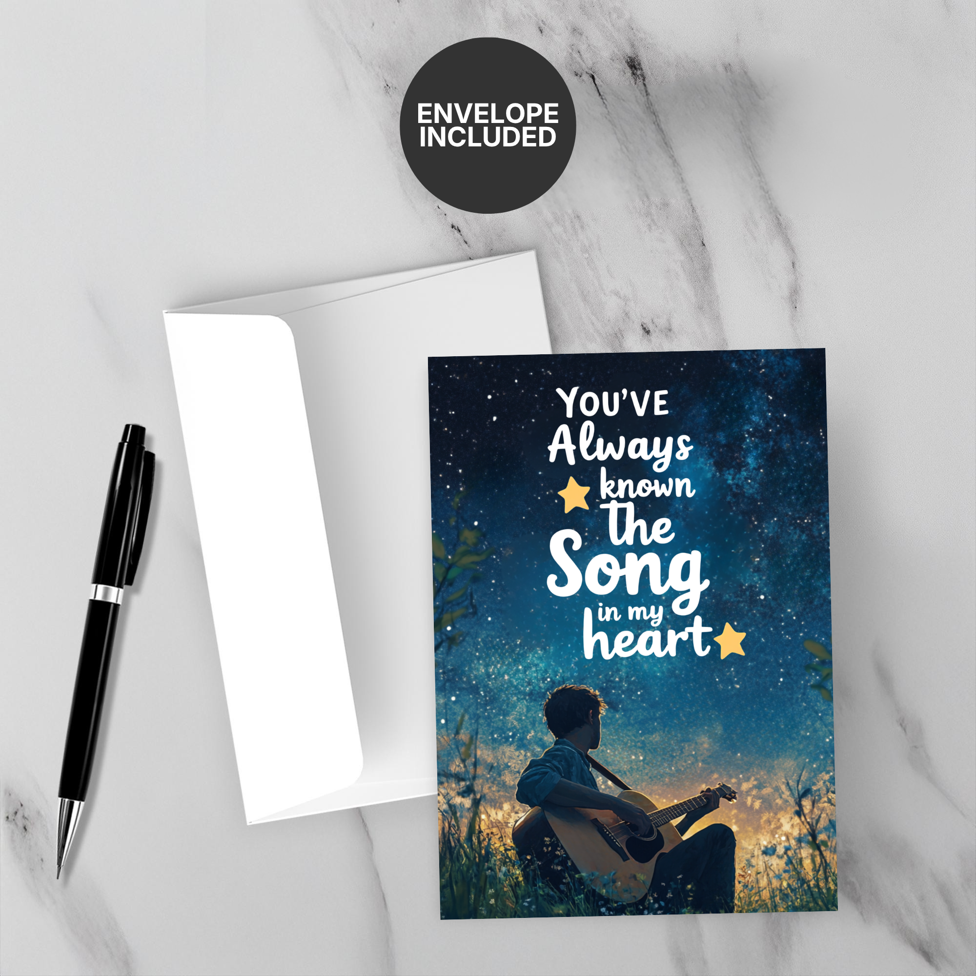 Greeting card with 'You've Always Known the Song in My Heart' text and a silhouette of a person playing guitar, accompanied by an envelope on a marble surface.