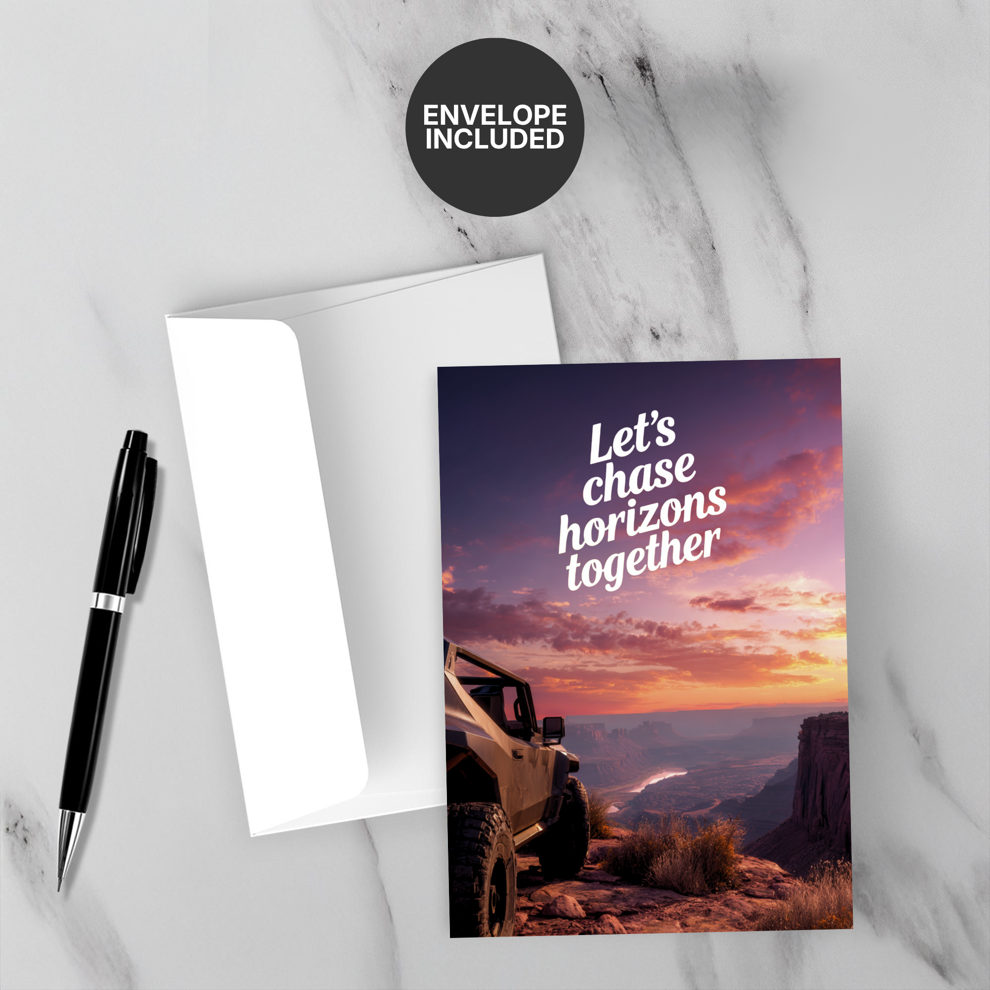 Greeting card with 'Let's chase horizons together' text and a jeep at sunset, accompanied by a pen and envelope on a marble surface.