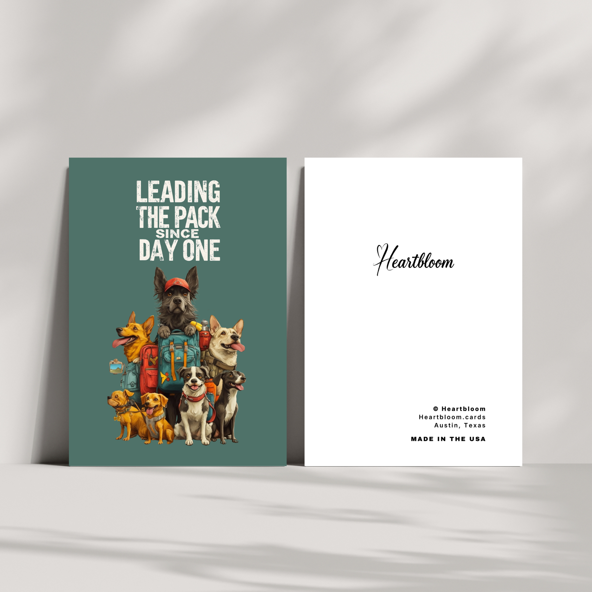 Two greeting cards on a white surface, one with a green background and illustrations of dogs, the other with a white background and 'Heartbloom' branding.