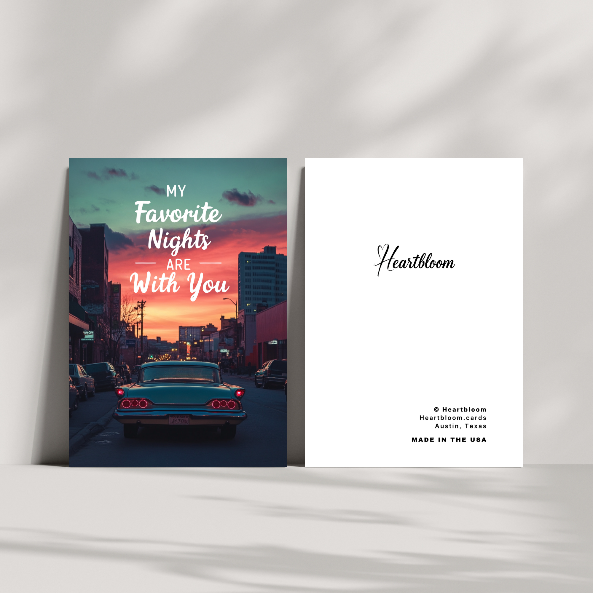 Two greeting cards on a white surface, one with a cityscape and 'My Favorite Nights Are With You' text, the other with 'Heartbloom' branding.