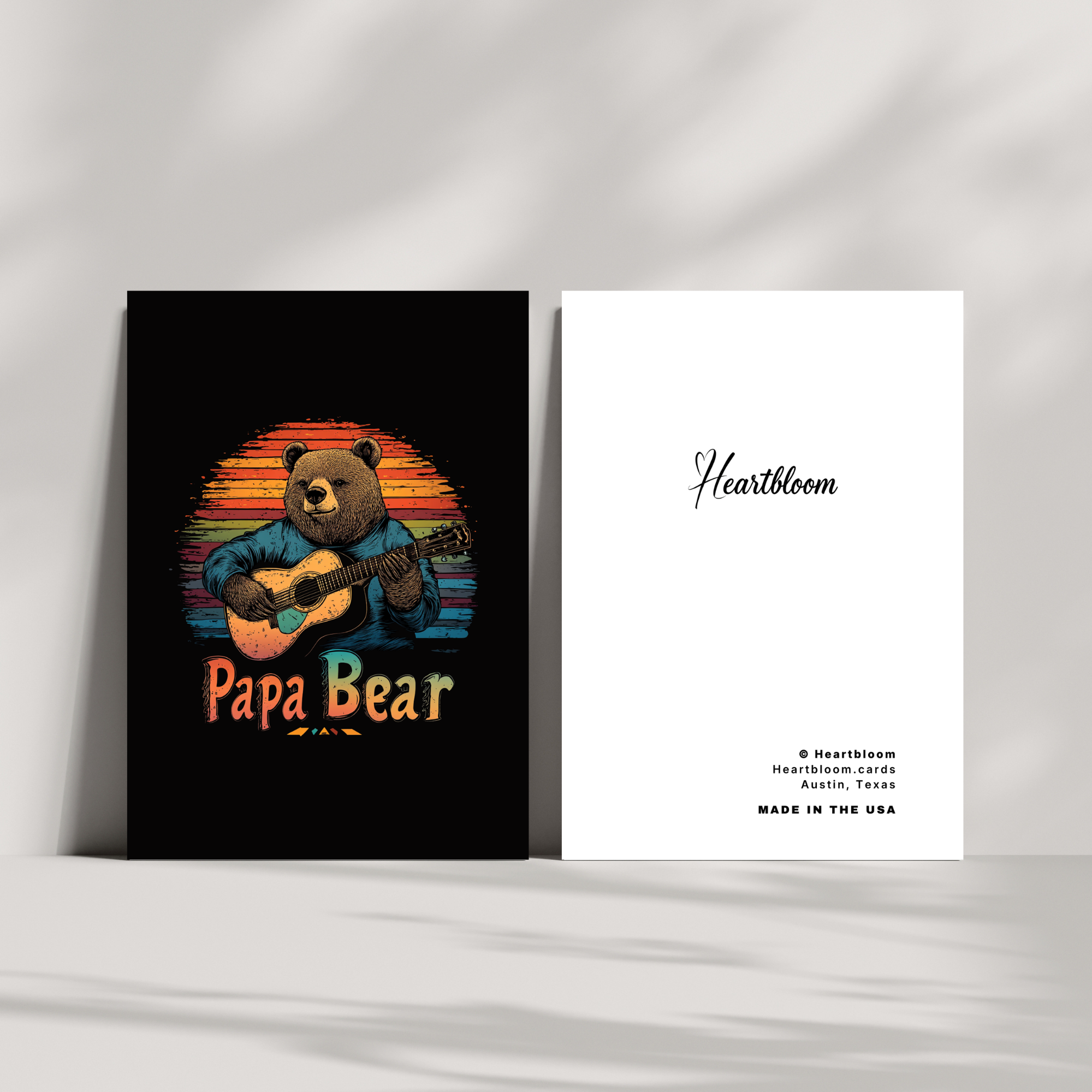 Card with 'Papa Bear' design featuring a bear playing guitar against a sunset background, with 'Heartbloom' branding on a white card.