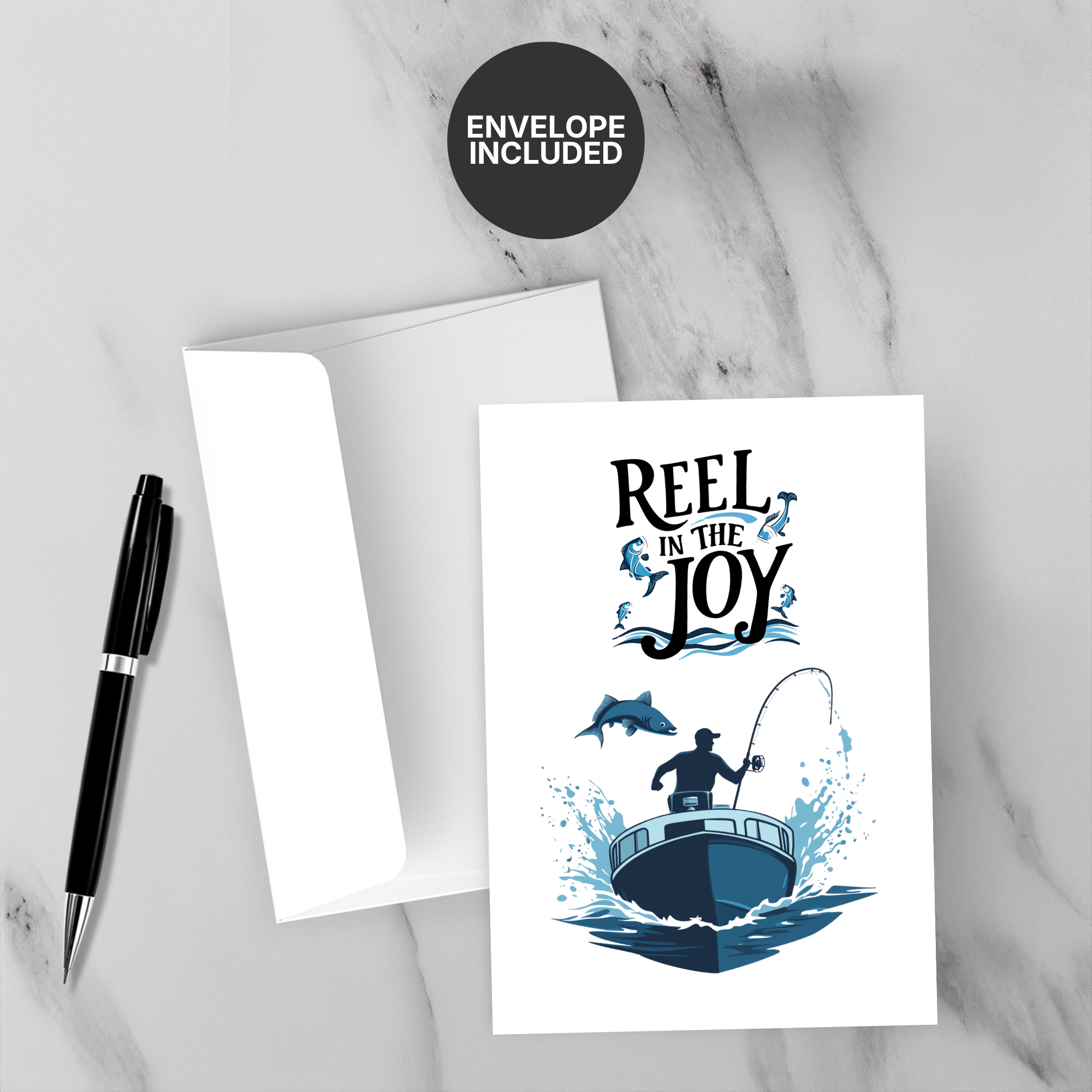 Greeting card with 'Reel in the Joy' design on a marble surface with a pen and envelope.
