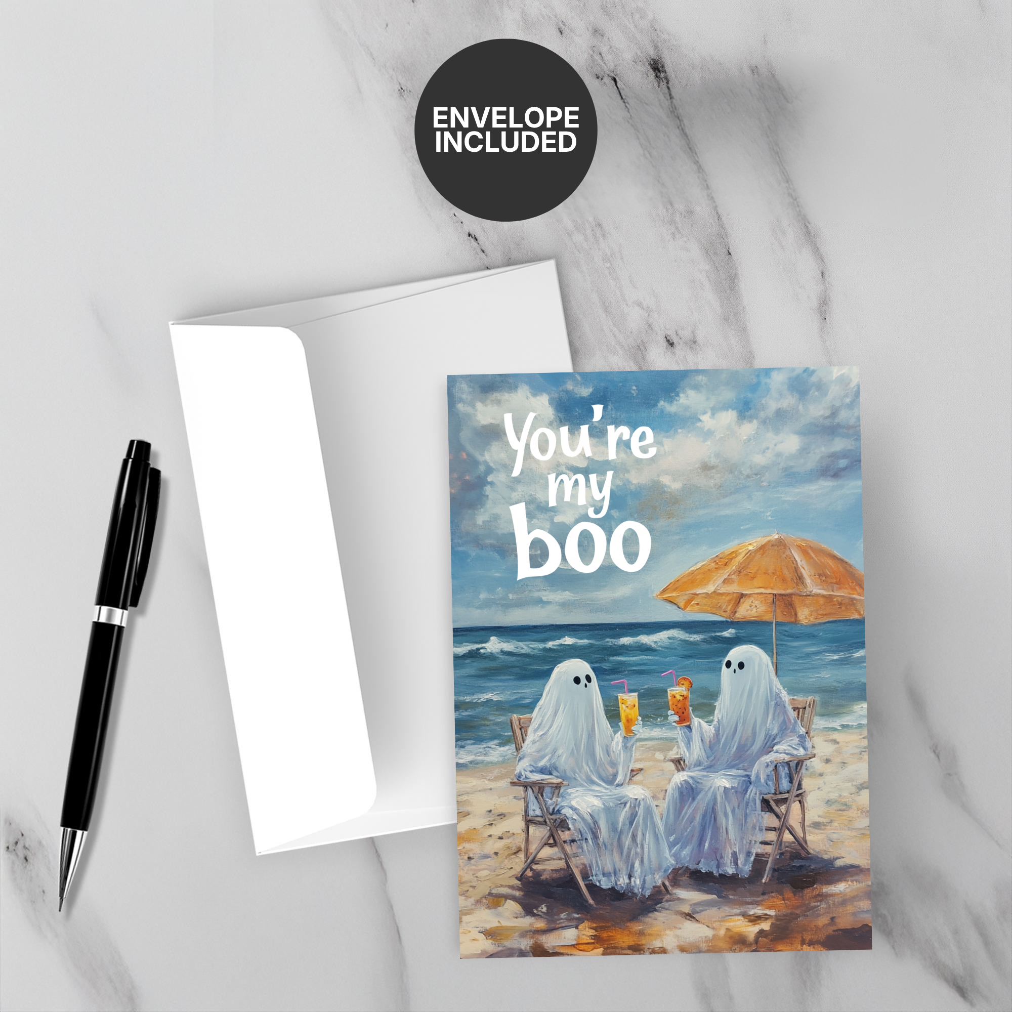 Greeting card with ghosts on a beach, 'You're my boo' text, and envelope on marble surface.