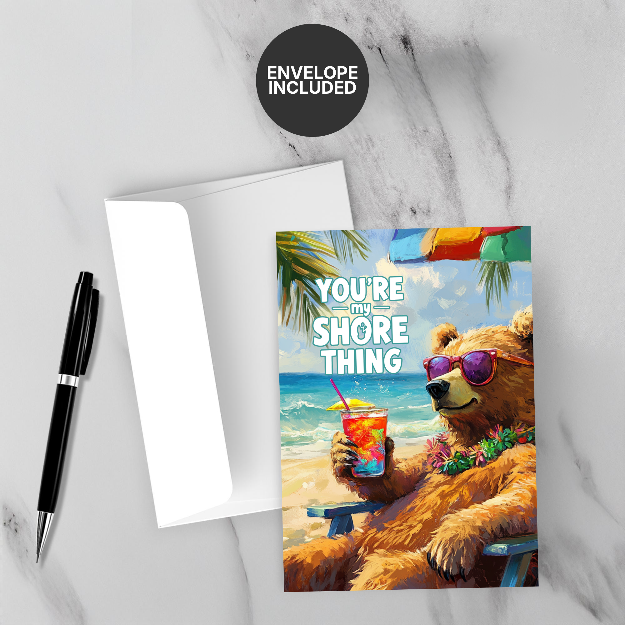Card with bear holding a drink on a beach, text 'You're my shore thing', envelope included, on marble surface.