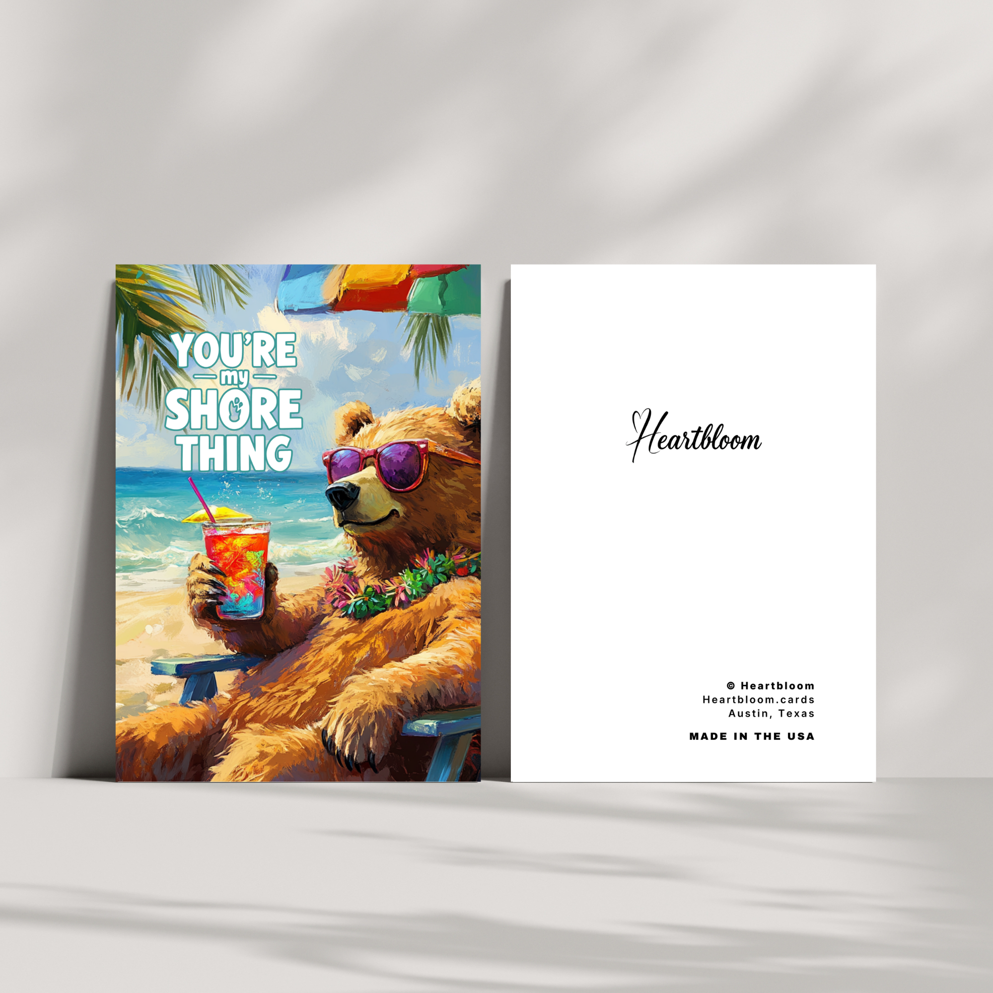 Card with a bear holding a drink on a beach, featuring the brand 'Heartbloom'.