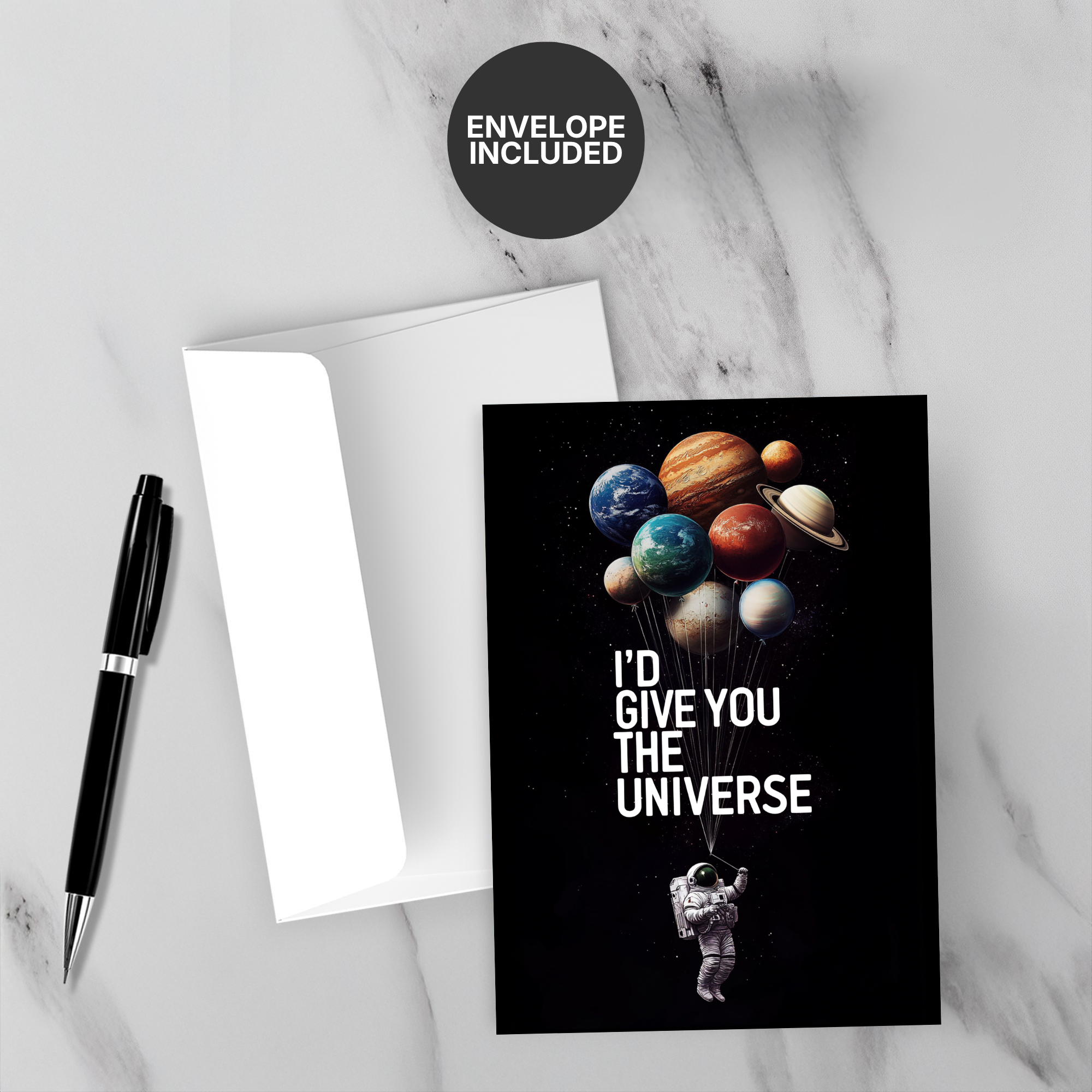 Greeting card with space-themed design and 'I'd give you the universe' text, accompanied by a pen and envelope on a marble surface.