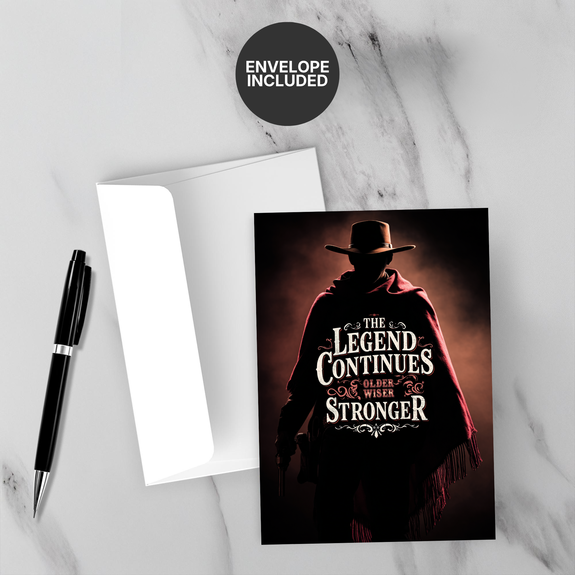 Greeting card with a cowboy silhouette and 'The Legend Continues' text on a marble surface with a pen and envelope.