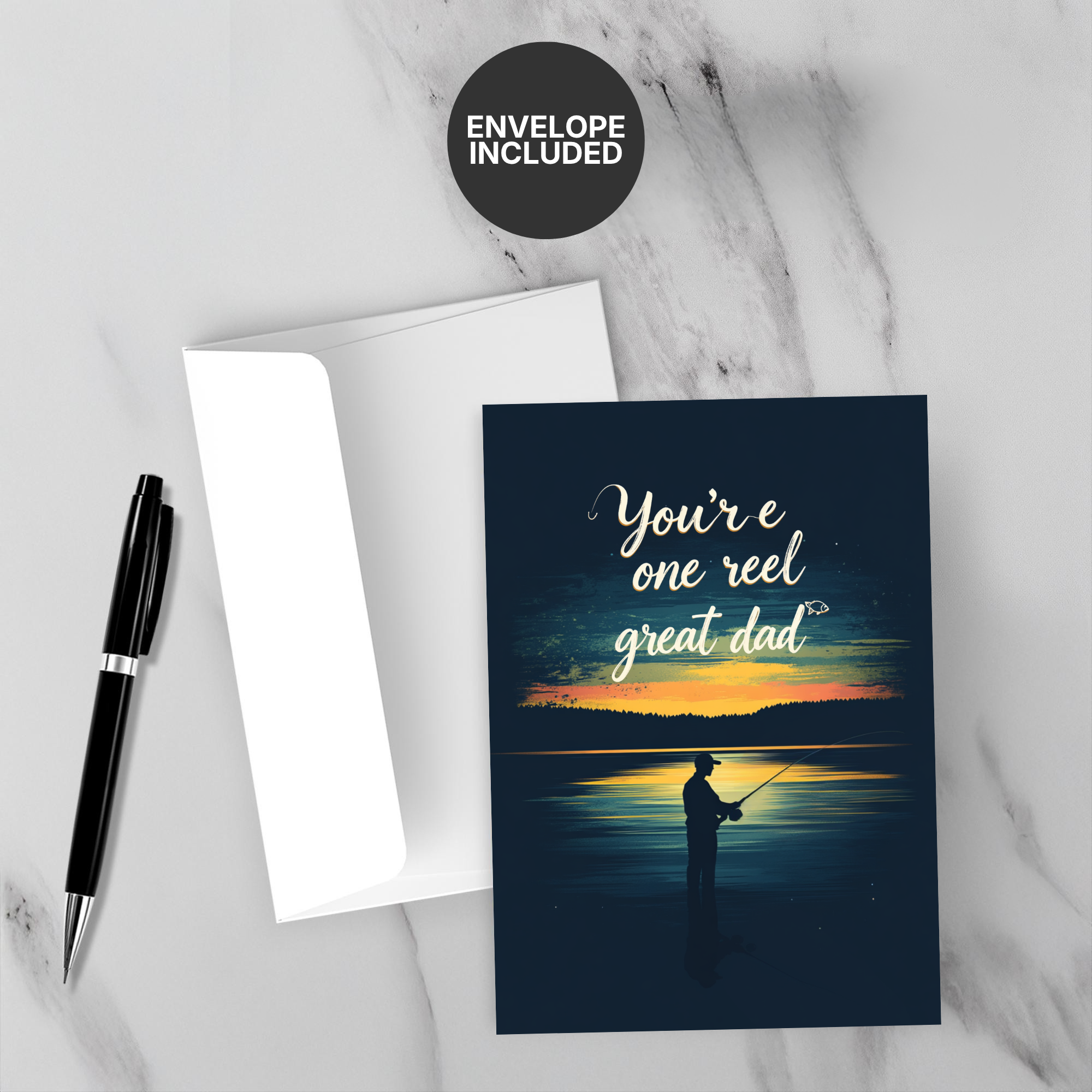 Greeting card with fishing design and text 'You're one reel great dad' on a marble surface with a pen and envelope.